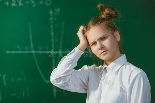 女孩在黑板背景上思考。 教育和学校理念