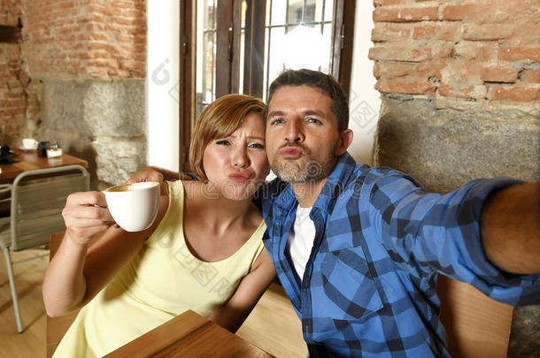 一对夫妇在咖啡店用手机拍自拍照片，在浪漫的爱情概念中微笑快乐