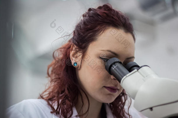 女医生通过显微镜在实验室里观察的女医学或科学研究人员或女医生。年轻科学家