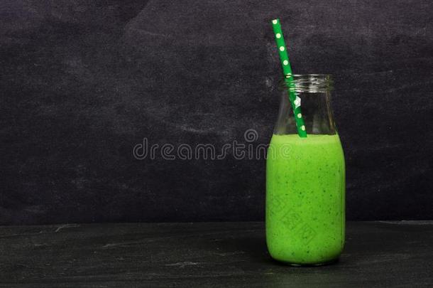 绿色的冰沙在一个<strong>牛奶瓶</strong>中抵着石板