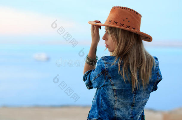 牛仔西部风格的美女，牛仔帽和牛仔裤夹克，时尚肖像摄影，广告，海景土地