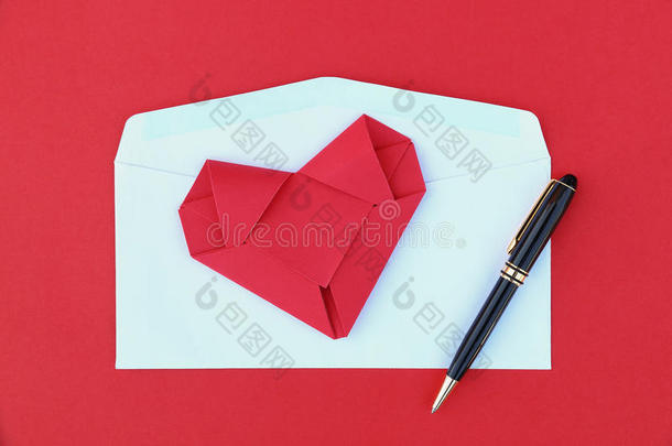 在白色<strong>信封</strong>和<strong>黑</strong>色商务笔上折叠红纸心