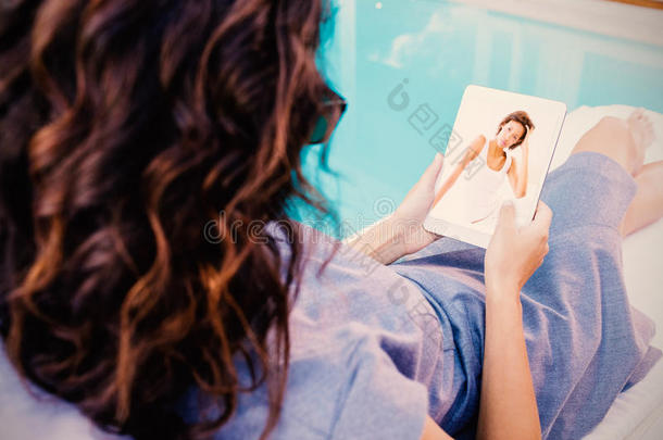 美丽的黑发女人坐在床上看相机的复合图像