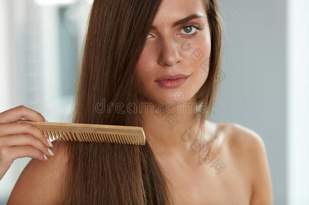 刷头发。 女人用梳子刷漂亮的长发