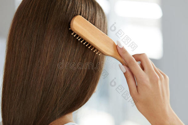 健康长发的女人用刷子刷它的背面视图