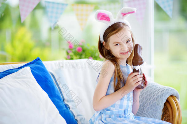可爱的小女孩戴着兔子耳朵吃巧克力复活节兔子
