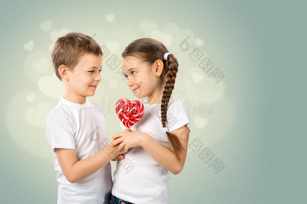 男孩给了一个小女孩心形的糖果红色棒棒糖。 情人节`