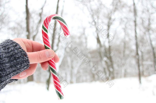 手拿糖果拐杖。 下雪的圣诞节景观。 背景的模糊照片。