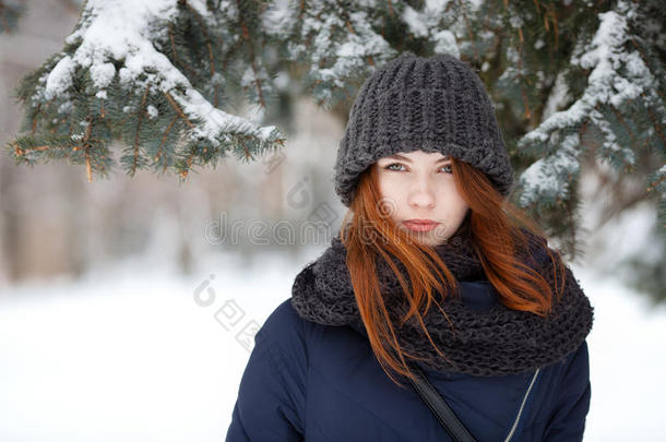 特写美丽的冬天肖像，年轻可爱的红头发女人穿着可爱的针织帽子，冬天的雪公园