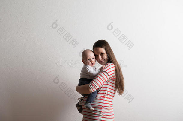 美丽的母亲抱着小儿子。 摄影棚拍摄。