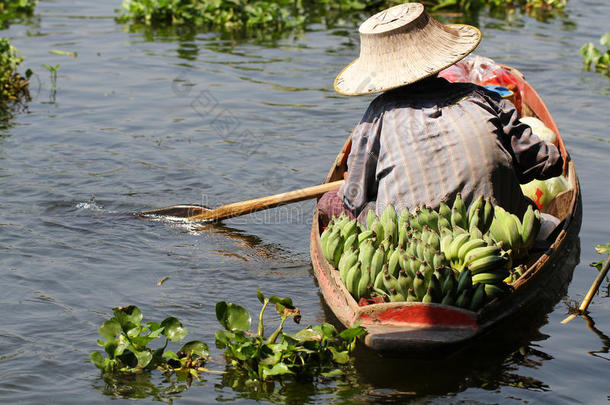 农民在小船上工作，在浮动市场的河流上出售有机新鲜香蕉