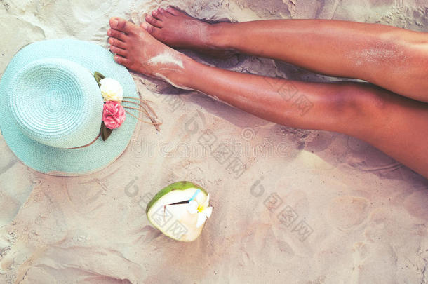 漂亮的女人晒黑了。 在沙滩上用帽子和<strong>椰子鸡尾酒</strong>放松。