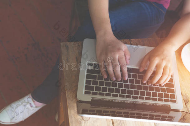 漂亮的年轻时髦女人`手忙着拿笔记本电脑，坐在咖啡店的木桌上
