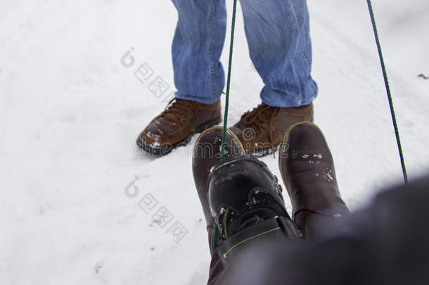 父亲幸运的家人骑着雪橇。 只穿鞋子的脚。