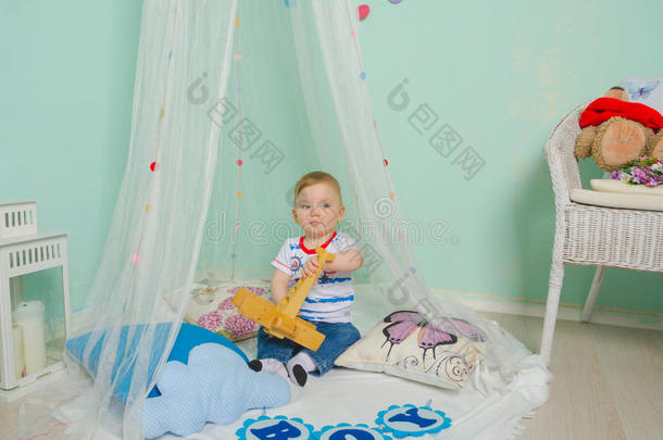 小男孩坐在地板上的浴帘下玩耍