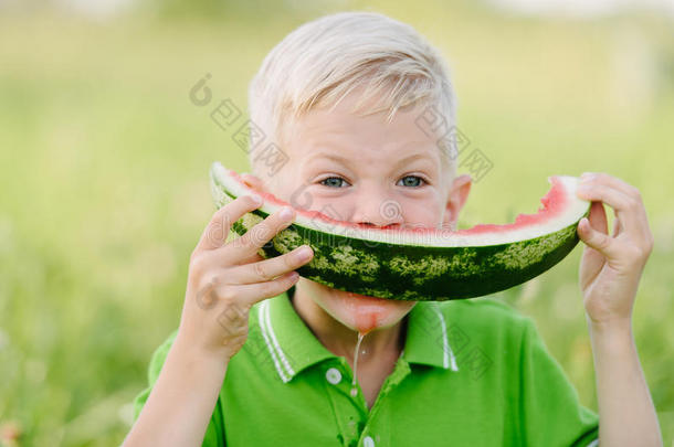 可爱的小男孩，金发在夏末花园吃西瓜