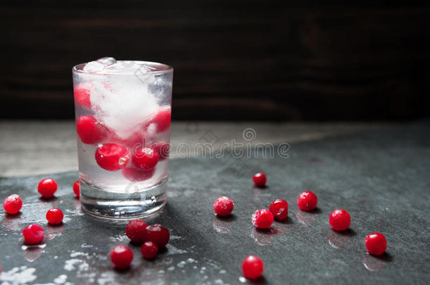 特写与新鲜蔓越莓，一杯俄罗斯伏特加和冰块在黑色背景水滴