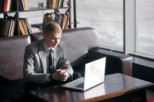 一个男人坐在一张桌子上拿着笔记本电脑