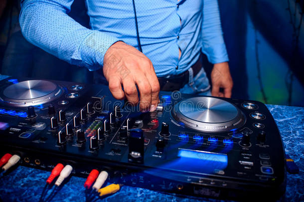 DJ手控制音量和混合音乐在专业搅拌机在夜总会的聚会