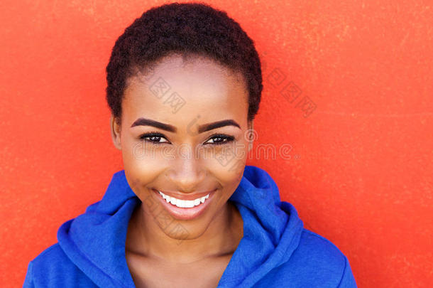 美丽的年轻黑人时尚女人对着红墙微笑