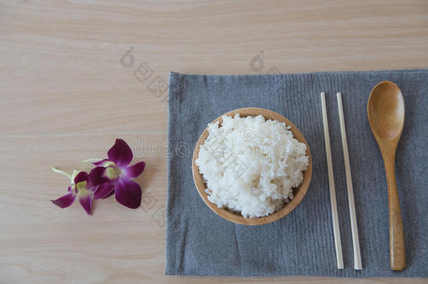 把米饭放在木碗和<strong>勺子</strong>里，<strong>筷子</strong>放在木头背景上。