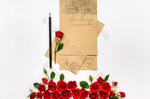 白色背景上有红色玫瑰的空纸张。 平躺，俯视