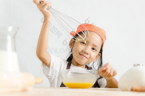亚洲小女孩用不锈钢搅拌器搅拌鸡蛋