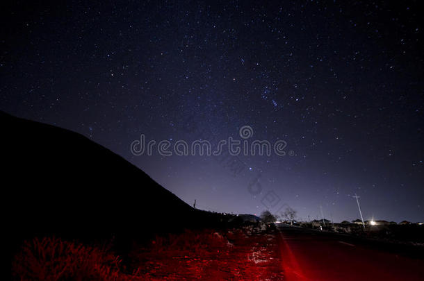 美丽的夜景，星星在天空和山脉轮廓附近的道路与汽车小径。 山中的道路在繁星下