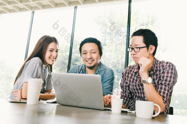 一群年轻的亚洲商业同事或大学生在团队非正式讨论中使用笔记本电脑