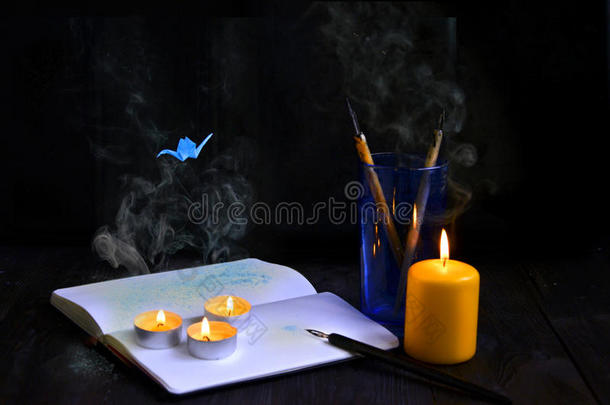 古老的木制背景上的蜡烛与烟雾和折<strong>纸鹤</strong>