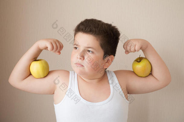 穿着t恤的胖男孩展示了他的二头肌上有苹果的肌肉