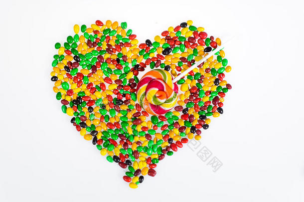 彩色果冻豆分散在一个心脏的形状和一个棒棒糖的形式，箭头在白色的背景。