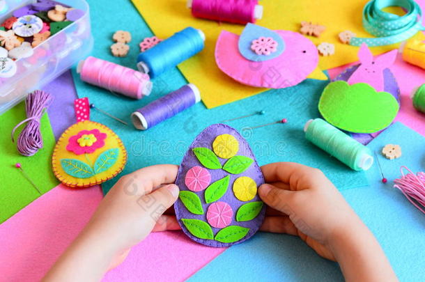 孩子用毛毡做复活节彩蛋的装饰。小孩手里拿着一个复活节彩蛋。复活节工艺品套装