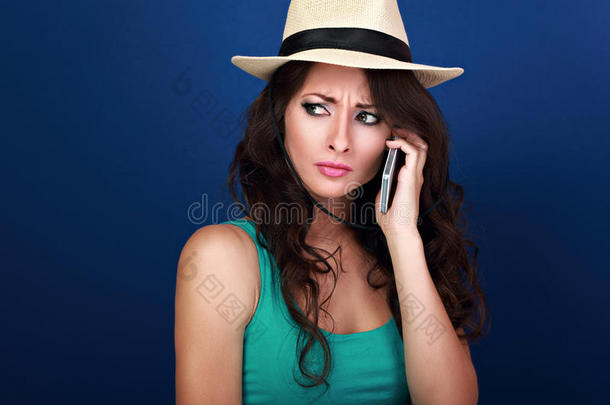 阴郁、不幸、沮丧的女人在夏天的帽子里在手机上聊天