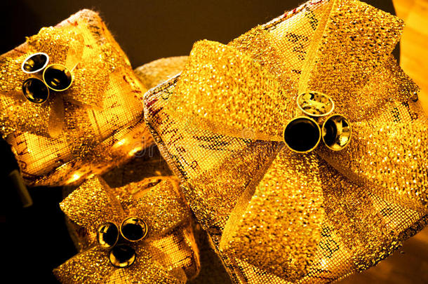三个闪闪发光的圣诞包裹，带着<strong>金色</strong>的大蝴蝶结和<strong>铃铛</strong>