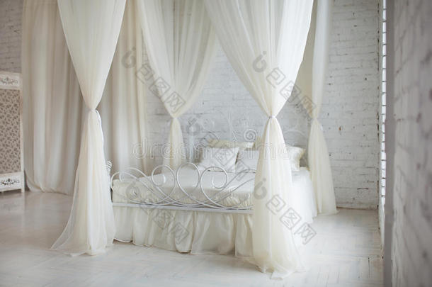 卧室采用柔和的浅色。 大舒适优雅的双人床在白色砖阁楼内部与大窗户