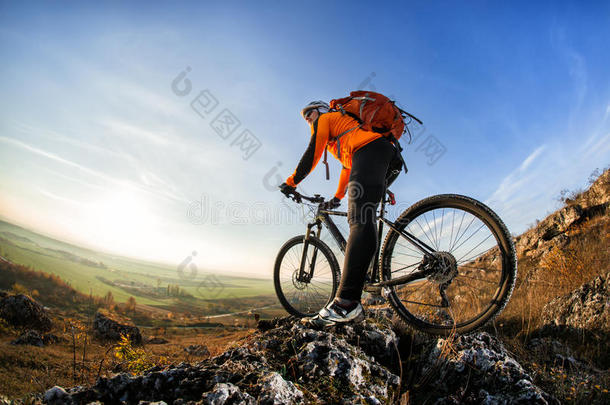 骑自行车的人站在山顶，骑着自行车，在晴朗的日子里，在蓝天下欣赏山谷的景色