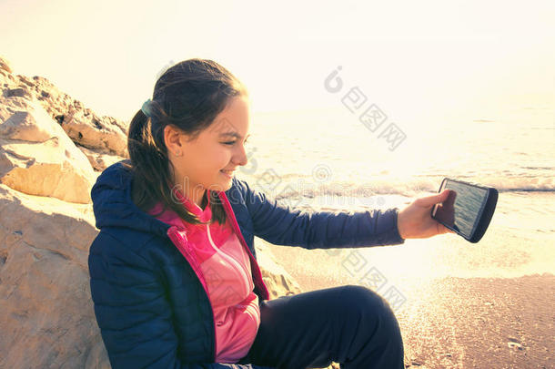 女孩拿着手机在海上自拍