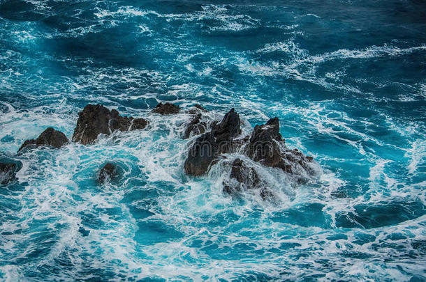 蓝色汹涌的海浪拍打着岩石