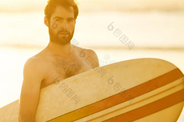 英俊的留着胡子的冲浪者，手臂下拿着一个复古的冲浪板