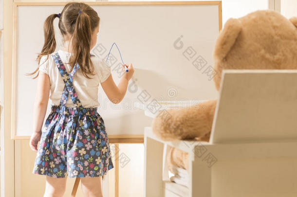 可爱的幼儿用她的玩具玩老师角色游戏