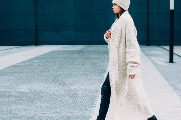 时尚时尚的女孩，戴着白色的帽子和针织外套。 在街上散步。 户外。 <strong>街头风</strong>格。