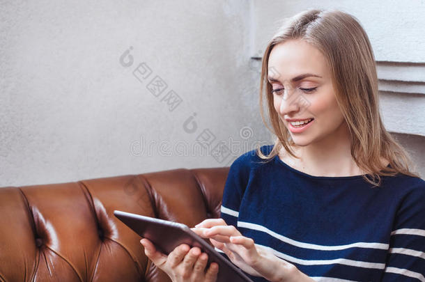 咖啡馆城市生活方式女人在平板电脑上发短信在平板电脑应用程序上坐在室内时尚的城市咖啡馆。