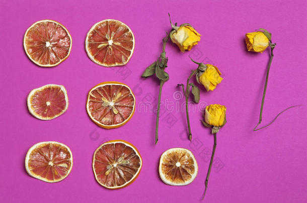 干橙和柠檬片与黄色玫瑰在勃艮第背景作为一种艺术作品，可用于装饰