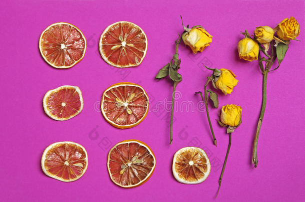 干橙和柠檬片与黄色玫瑰在勃艮第背景作为一种艺术作品，可用于装饰
