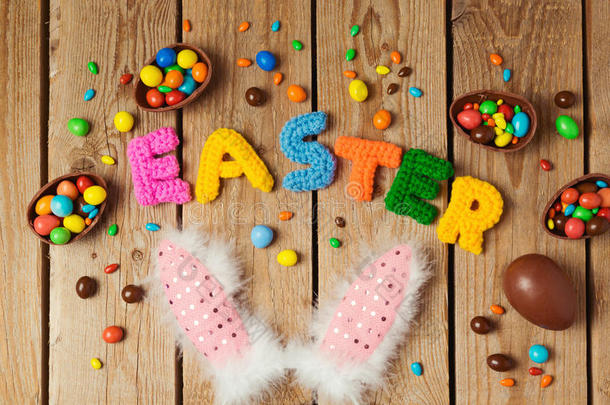 复活节假期概念与巧克力鸡蛋和兔子耳朵在木制背景。