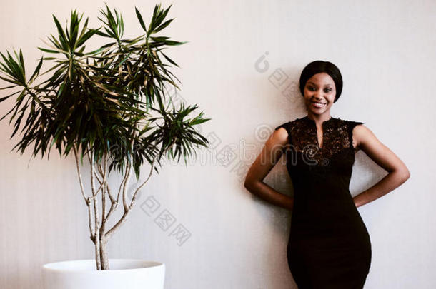 黑人女人站在植物旁边对着相机微笑