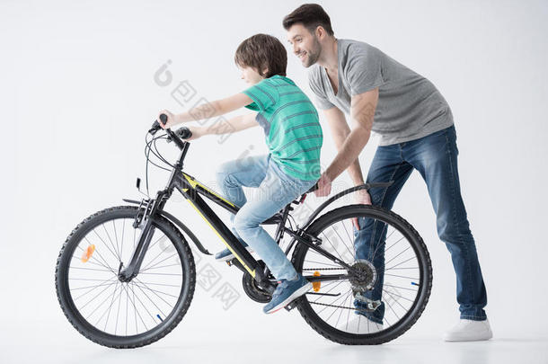 <strong>父亲帮助</strong>儿子骑自行车骑白色