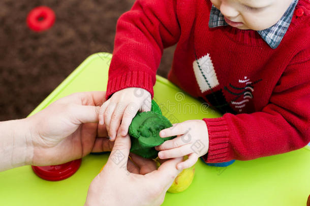 孩子们`手拿着绿色的粘土