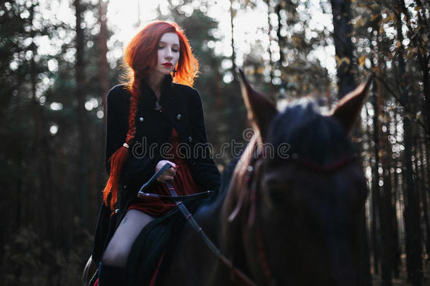 勇敢的红头发女孩穿着一件黑色的外套和一件留着长发的红色连衣裙，聚集在辫子里
